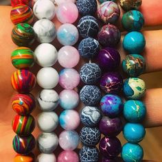 a person holding several different colored marbles in their hands