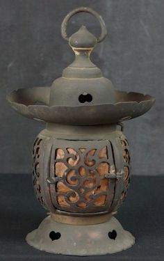 an old fashioned lantern is sitting on a black surface with holes in the top and bottom