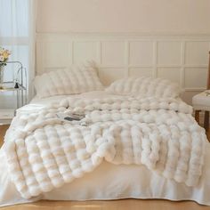 a bed with white fur on it in a room next to a chair and table