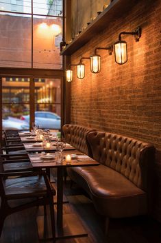 a long table with candles on it in front of a brick wall and wooden benches