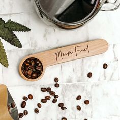 a wooden spoon filled with coffee beans on top of a counter next to a pot