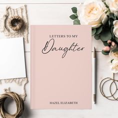 a pink book with the words, letters to my daughter on it next to some flowers