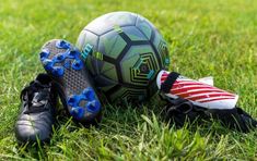 a soccer ball and shoes laying on the grass