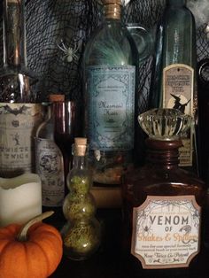 an assortment of liquor bottles and candles on a table with spider web in the background