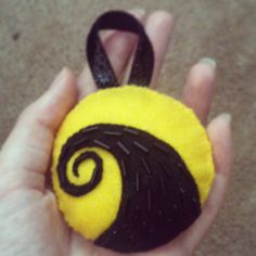 a hand holding a small yellow and black ball with a spiral design on it's side