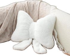 a white pillow with a bow on it's side and two pillows in the back