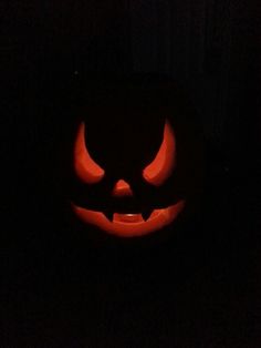 a lit up pumpkin in the dark with its eyes glowing orange and black at night