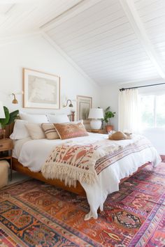 a large bed sitting in the middle of a bedroom on top of a colorful rug