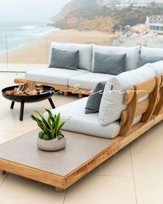 a couch and table sitting on top of a tiled floor next to a balcony overlooking the ocean