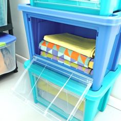 a stack of folded towels sitting on top of a blue shelf next to a plastic container