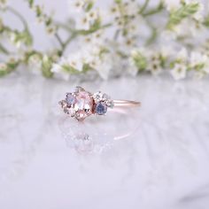 three stone ring sitting on top of a table next to flowers