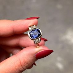 a woman's hand holding a ring with a blue stone