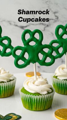 cupcakes with green frosting and shamrock decorations on top are sitting on a plate