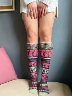 a woman standing on top of a bed with her legs in knitted socks and knee high socks