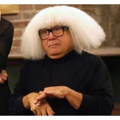 an old woman with white hair and glasses sitting in front of a man wearing a black suit