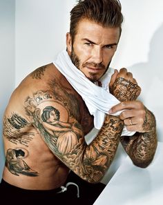 a man with tattoos on his arms and chest holding a white shirt over his shoulder