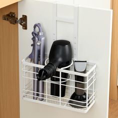 a kitchen cabinet door is open with hair dryers and other items in the holder