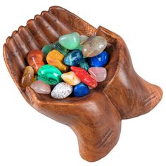 a wooden bowl filled with lots of colorful rocks