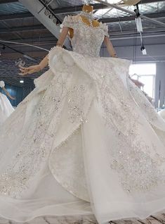 a white wedding dress is on display in a room with mannequins and other dresses