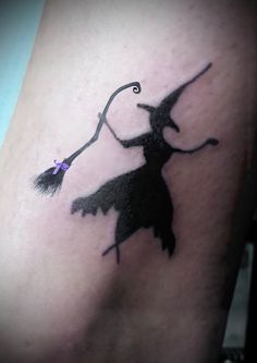 a woman's leg with a black silhouette of a witch holding a broom on it