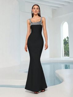 a woman in a black evening gown standing on a white floor next to a pool