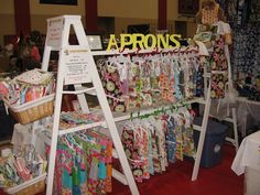 an assortment of items on display for sale at a craft fair, including aprons