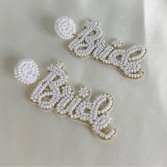 two beaded name brooches sitting on top of a white cloth