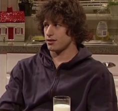 a young man sitting at a table with a glass of milk in front of him