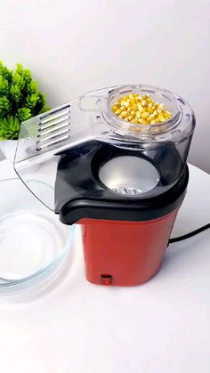 a red and black food processor sitting on top of a table next to a bowl