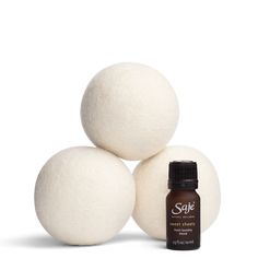 three balls of white wool sitting on top of each other next to a bottle of essential oils