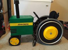 a green tractor with yellow wheels sitting on the floor