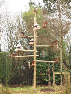 a tall wooden pole with lots of bird houses on it's sides and trees in the background