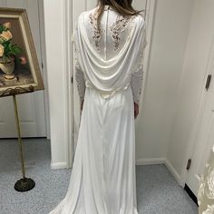 the back of a woman's wedding dress in front of a mirror with flowers on it