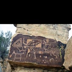 an ancient rock painting with horses and people on it, in the middle of some rocks