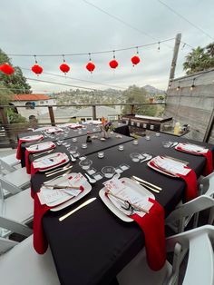 an outdoor dining area with black table cloths and red napkins on the tables