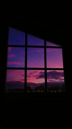 an open window at night with the sun setting in the distance and purple clouds outside