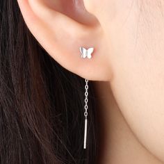 a close up of a person wearing a pair of earrings with chains attached to them