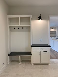 an empty room with white cabinets and black counter tops in the center is a bench