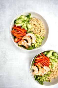 two bowls filled with rice and vegetables on top of a white tablecloth next to each other