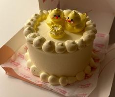 there is a cake with yellow frosting and two small birds on top of it