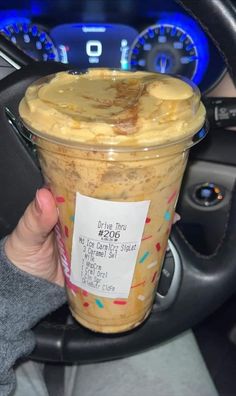 a person holding up a cup of food in their hand with a price tag on it