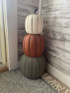 three stacked pumpkins sitting on top of each other in front of a wooden wall