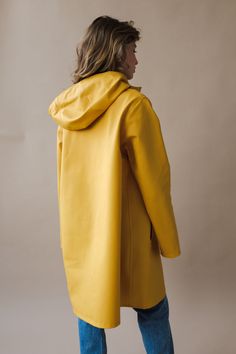 Stutterheim Mosebacke Warm Honey yellow raincoat is the A-line version of Stutterheim's iconic raincoat. A definite feminine style in the a-line silhouette – but with the same 100% rainproof heavy-weight original 530-gram rubberised cotton, double-welded seams and snap metal closures. Also features a drawstring hood, front welt pockets and under-arm eyelets for ventilation. Named after a fashionable and bohemian part of Stockholm, Mosebacke combines a relaxed fit with a minimalist yet feminine l Stutterheim Mosebacke, Guy Cotten, Rainwear Girl, Coraline Jones, Honey Yellow, Wind Protection, Yellow Raincoat, Stockholm Style, Rain Jacket Women