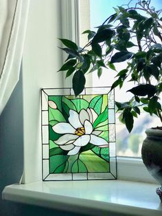 a potted plant sitting on top of a window sill next to a stained glass flower