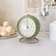 an alarm clock sitting on top of a table next to a wine glass and plate