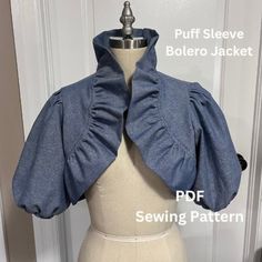 the back of a blue jacket with ruffles on it, sitting on a mannequin