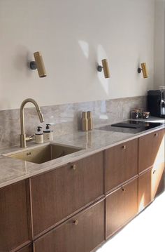 a kitchen with wooden cabinets and marble counter tops, gold faucets on the backsplash