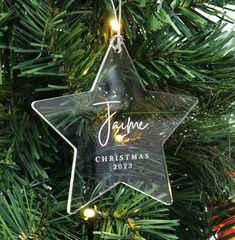 a glass star ornament hanging from a christmas tree with the name jamie on it