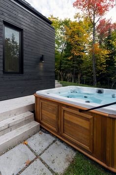 a hot tub sitting on top of a stone walkway next to a wooden building with steps leading up to it