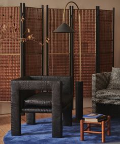 a living room with two chairs and a table in front of a bamboo screen wall